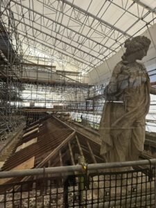 A view across a roof inside the scaffolding with a statue in the foreground